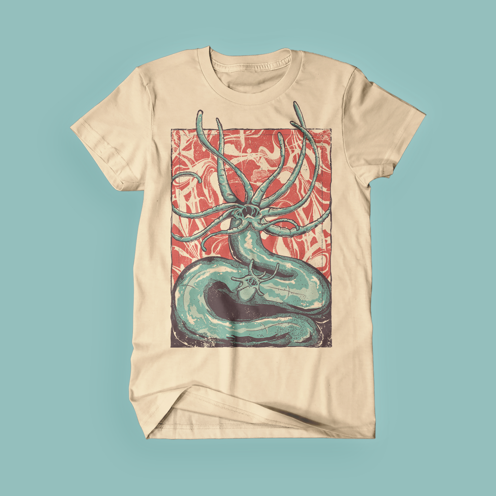 Photograph of a tan t-shirt featuring an illustration of a teal Hydra on a red background